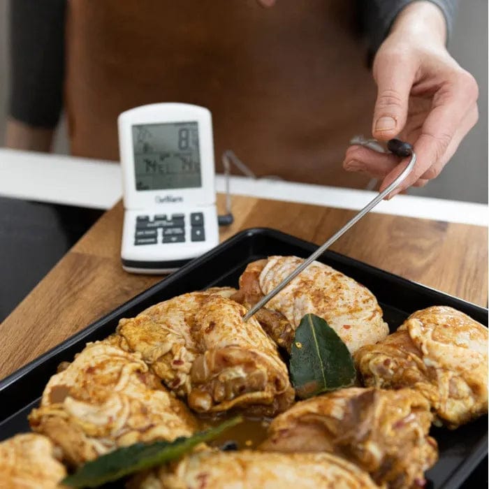Une personne utilise un Thermomètre ChefAlarm de Thermomètre.fr pour vérifier la température du poulet pendant la cuisson.